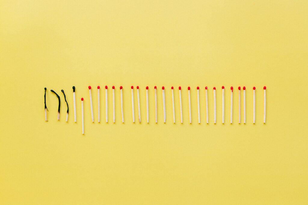 Yellow background with row of matches, some that are burned out.