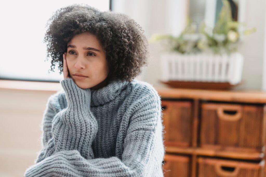 Woman in blue-gray sweater looking of into distance.